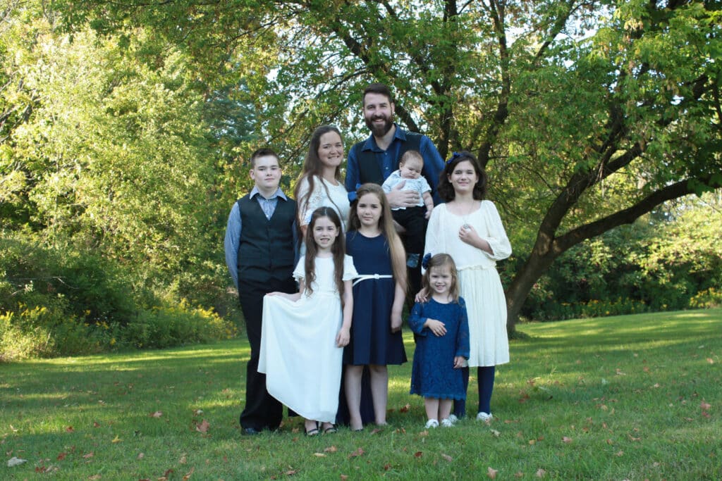 The Mallay family pictured in a family photograph outdoors on green grass with trees in the background